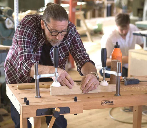 A woodworker clamping a workpiece in a Sjöbergs workbench