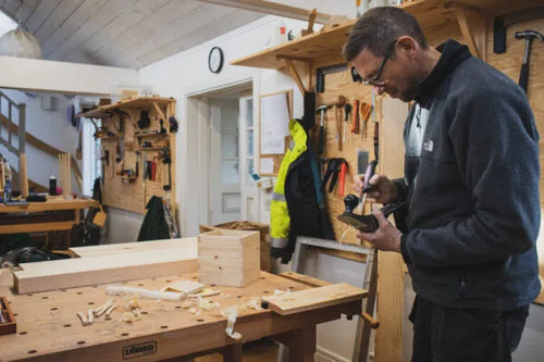 A man working with a tool in a workshop at Capellagården