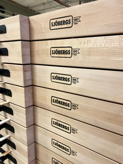 Stacked wooden crates with the Sjöbergs 100 years logo