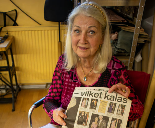 Inger Löwe holds up a newspaper article in her tailoring studio