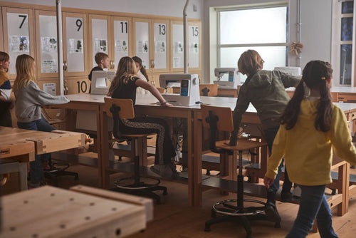 Pupils at workbenches and sewing machines in a craft classroom