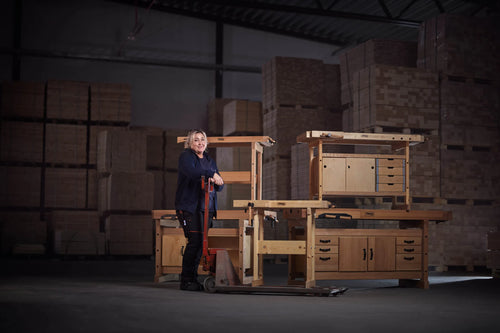 A person at a Sjöbergs workbench in a warehouse with stacked boxes