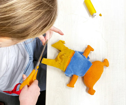 A child cutting a piece of fabric shaped like a figure
