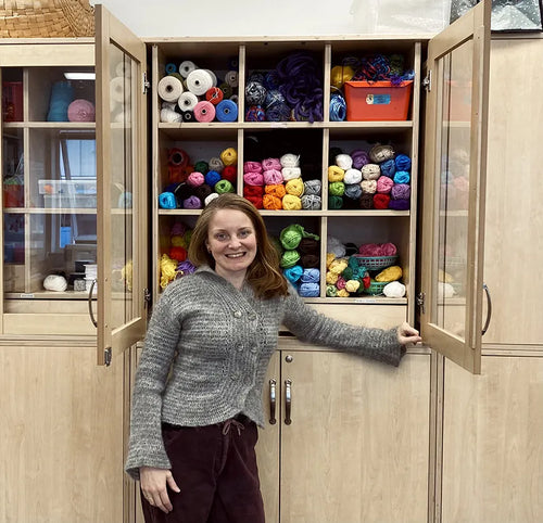 AnnaStina in front of an open cabinet full of yarn and fabric