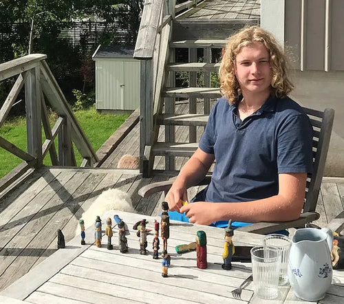 Adrian Nilsson Markung at a table with his carved wooden figures