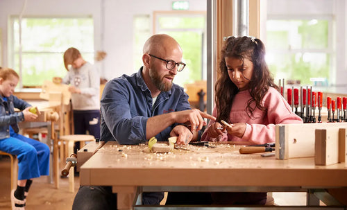 A teacher and pupils working at a workbench in a woodwork room