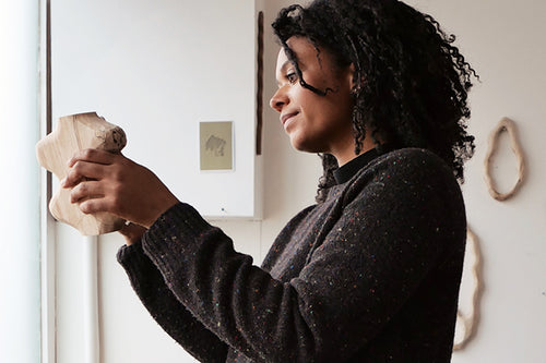 Sophie Sellu holds up a sculpture in cleft wood in her studio
