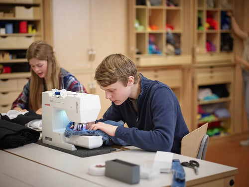 Pupils sewing at sewing machines in the textile classroom